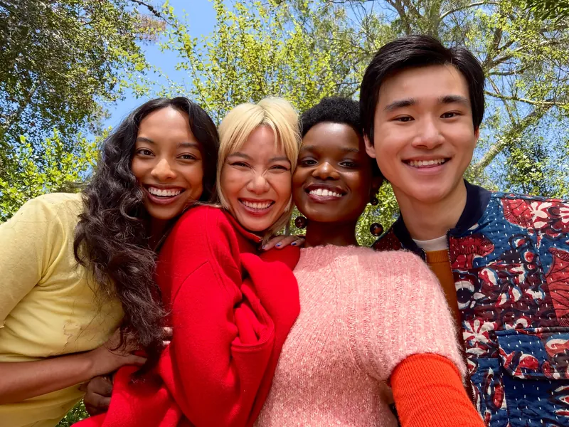 Four people smiling in an outdoor group selfie taken on iPhone Duo with the Center Stage front camera